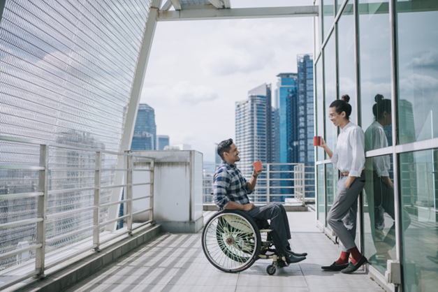 two men drinking tea, one is sitting on wheel chair another is standing