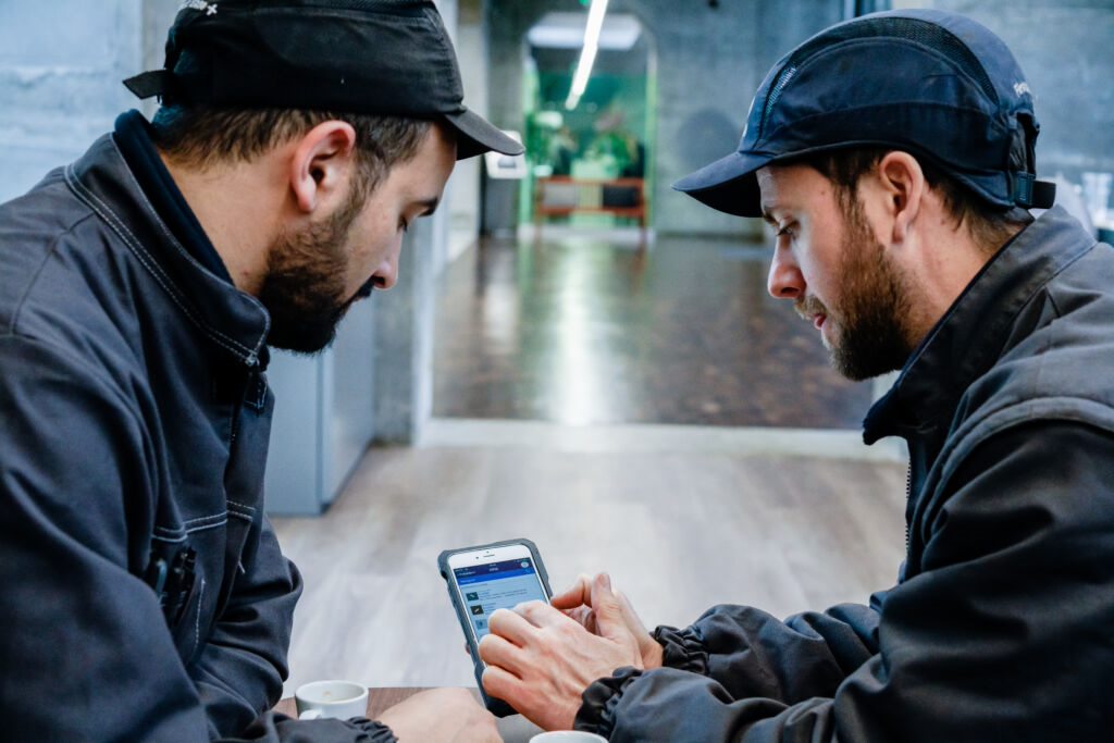 Two mechanics looking at the Otis ONE app