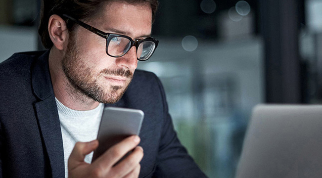 man holding phone seeing laptop