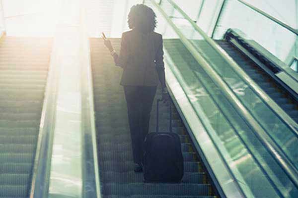 woman on escalator holding suitcase