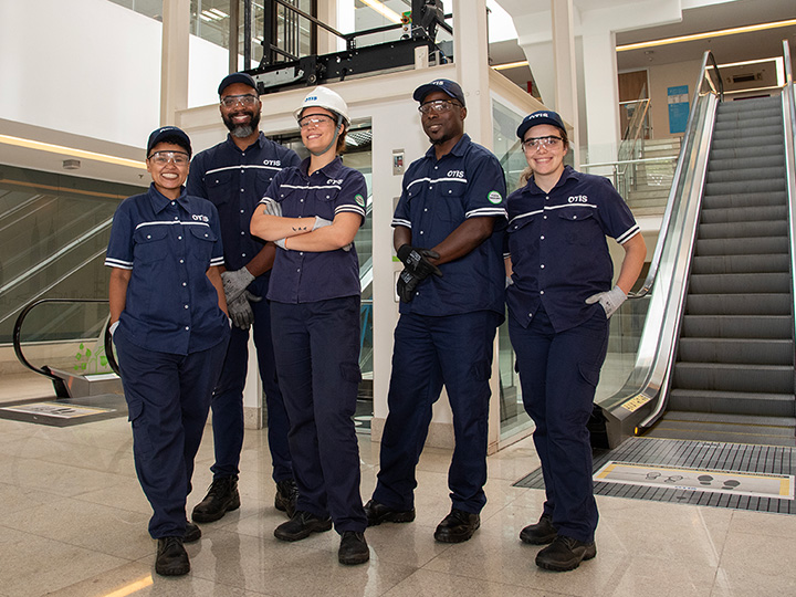 Otis employees posing in front of escalators