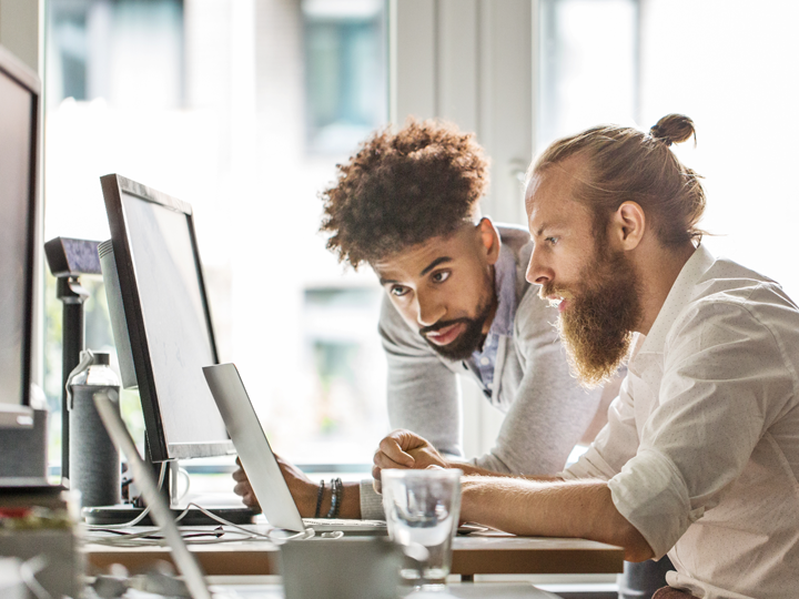 two men looking at laptop screen 