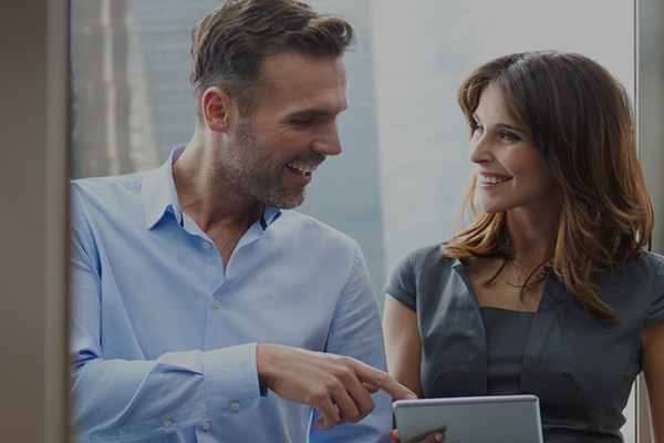man and woman smiling while man looking at Ipad
