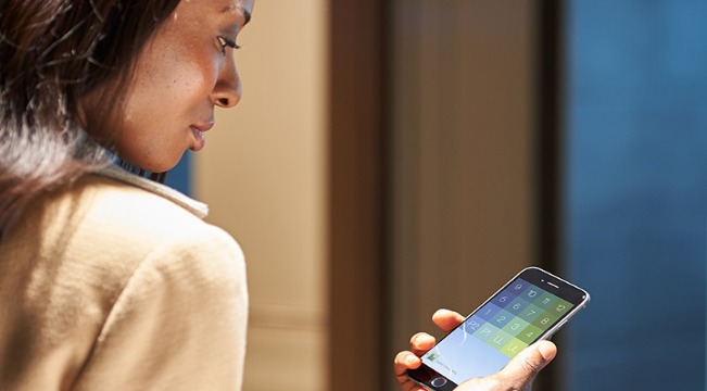 Lady holding a phone which is showing the eCall app.  eCall allows passengers to call the lift from their mobile devices as they approach 