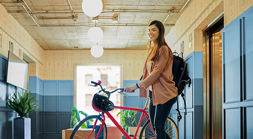 Woman walking a bike out of an elevator