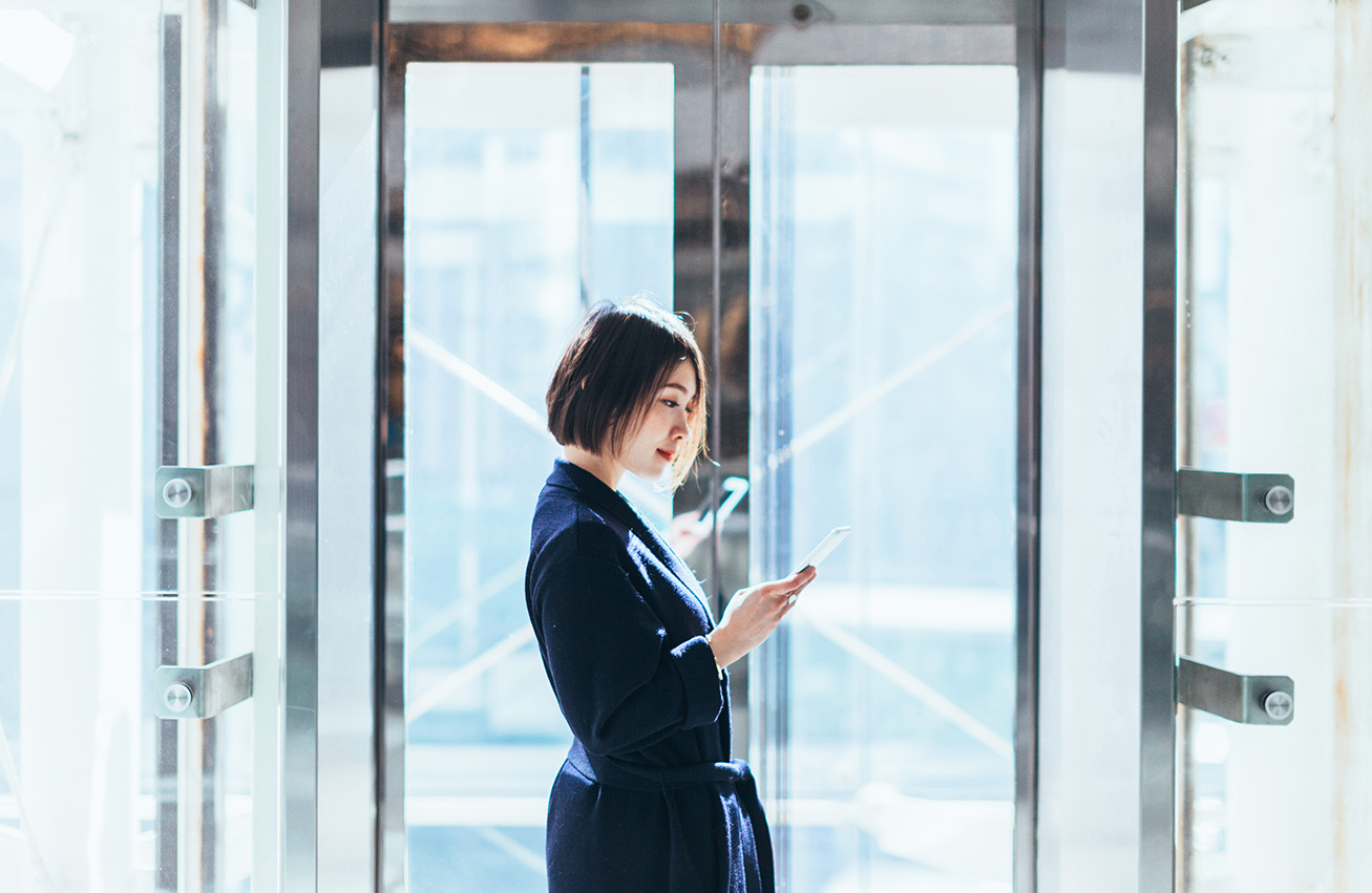 Woman in elevator looking at phone