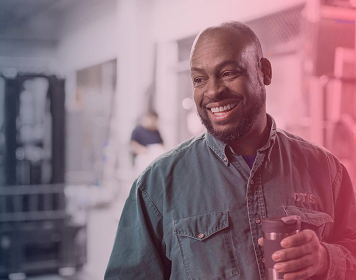 Male Otis employee smiling and holding a cup of coffee