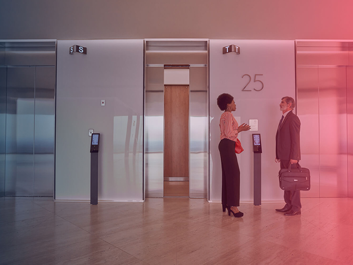 Business woman and business man standing in front of an elevator bank