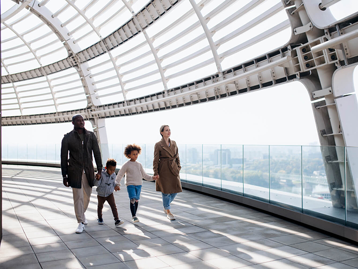 A family with two young kids holding hands in an airport hallway