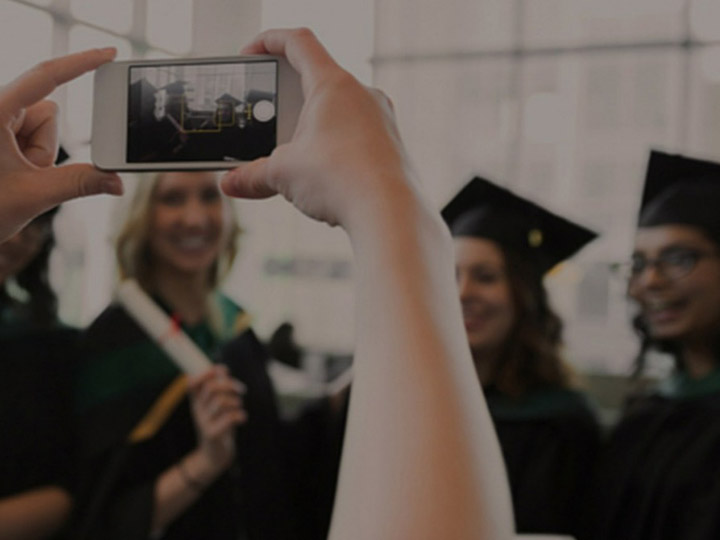 Person taking photo of graduates with iPhone loading=