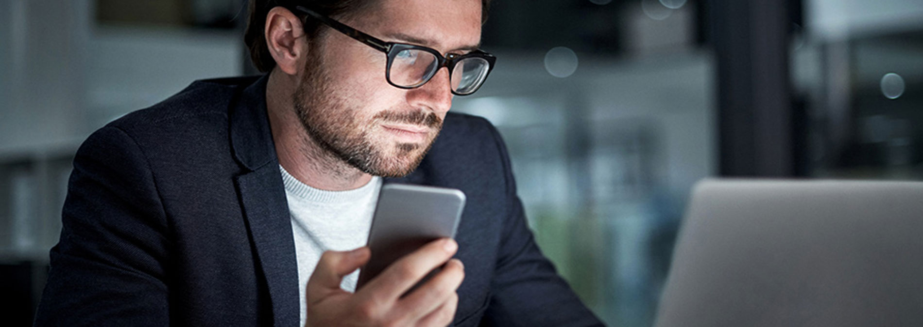 man holding phone seeing laptop