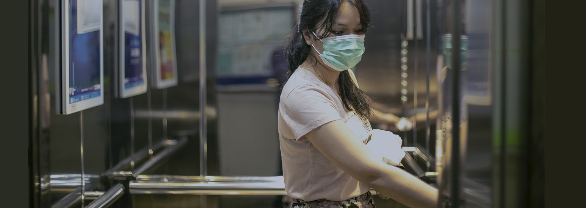 lady in mask pressing elevator button